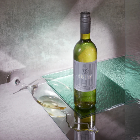 Wine bottle on a glass shelf with a glass of wine in the foreground