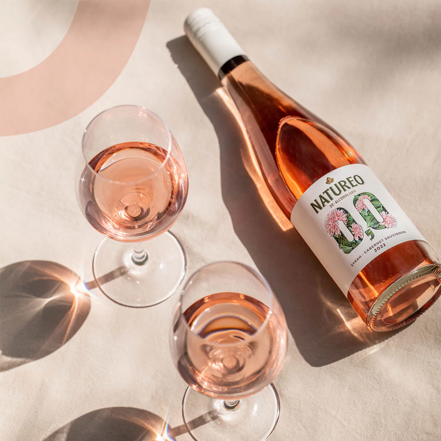 Bottle and glasses of rose wine with 'NATURERO' label on a light background