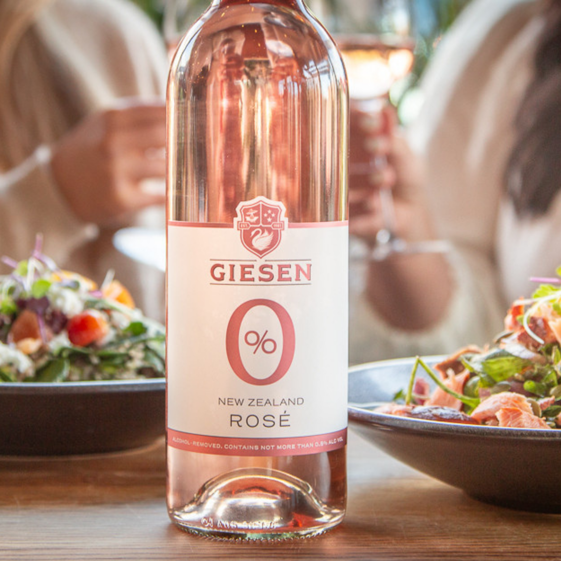 Bottle of Giesen New Zealand Rosé wine on a table with people and food in the background