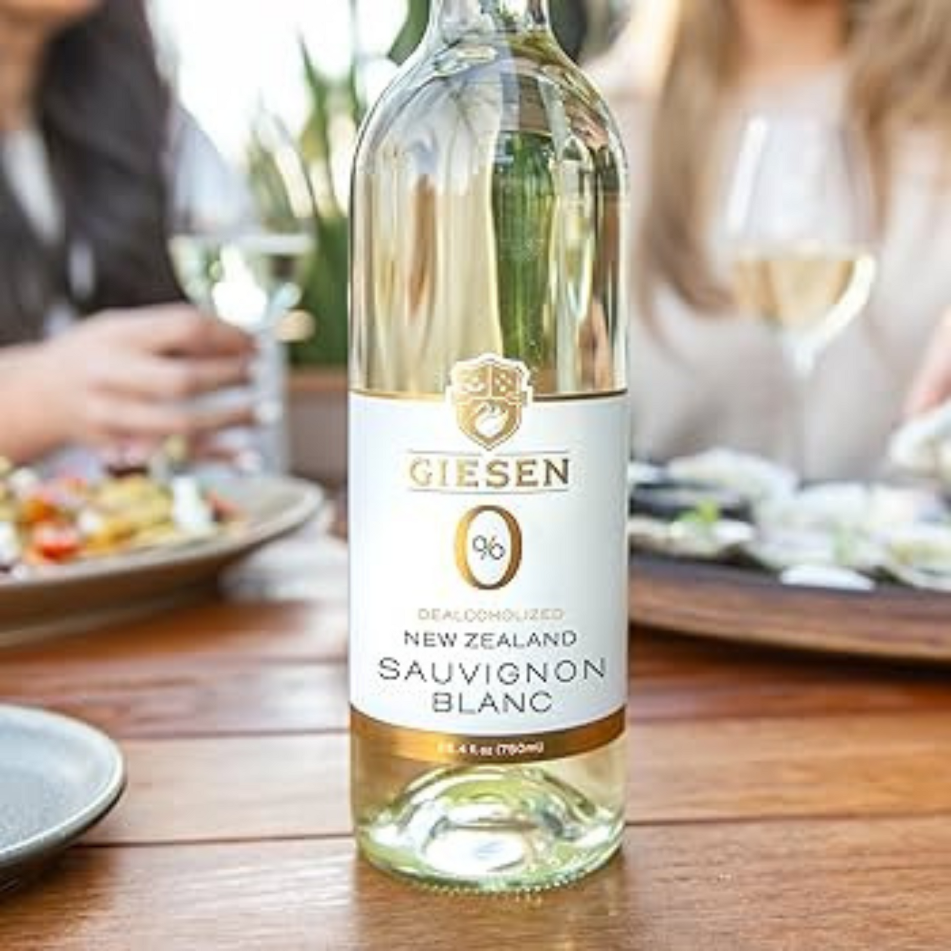 Bottle of Giesen 0% New Zealand Sauvignon Blanc wine on a table with people and food in the background