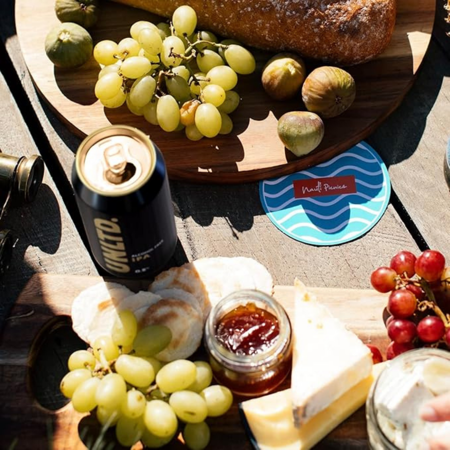 Wooden board with grapes, figs, bread, and a can of Unicel on a table.