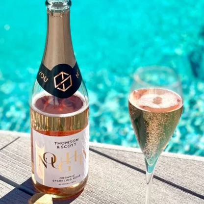 Bottle and glass of sparkling rose wine by a pool