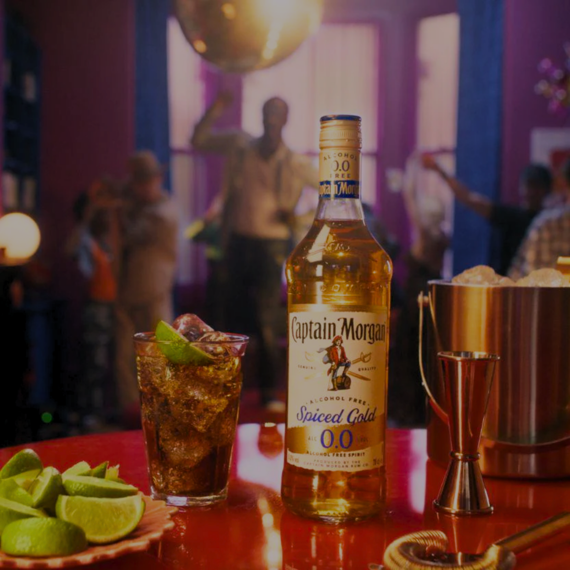 Captain Morgan Spiced Gold bottle with a cocktail on a bar counter in a lively bar setting