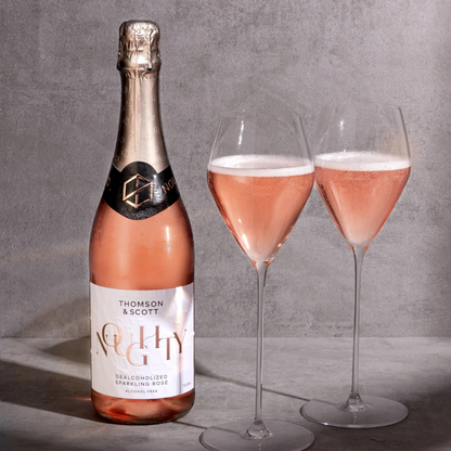 Bottle and two glasses of rose sparkling wine on a gray background