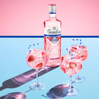 Pink alcohol-free gin bottle with glasses of strawberry cocktail on a pink and blue gradient background