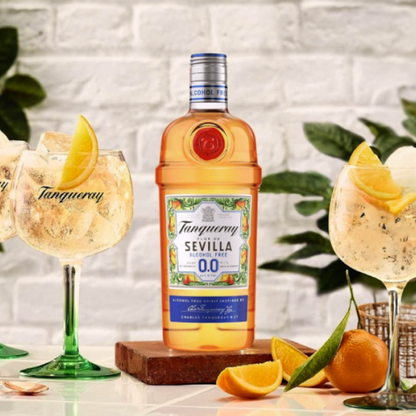 Tanqueray Sevilla 00 bottle with cocktails and garnishes on a table.