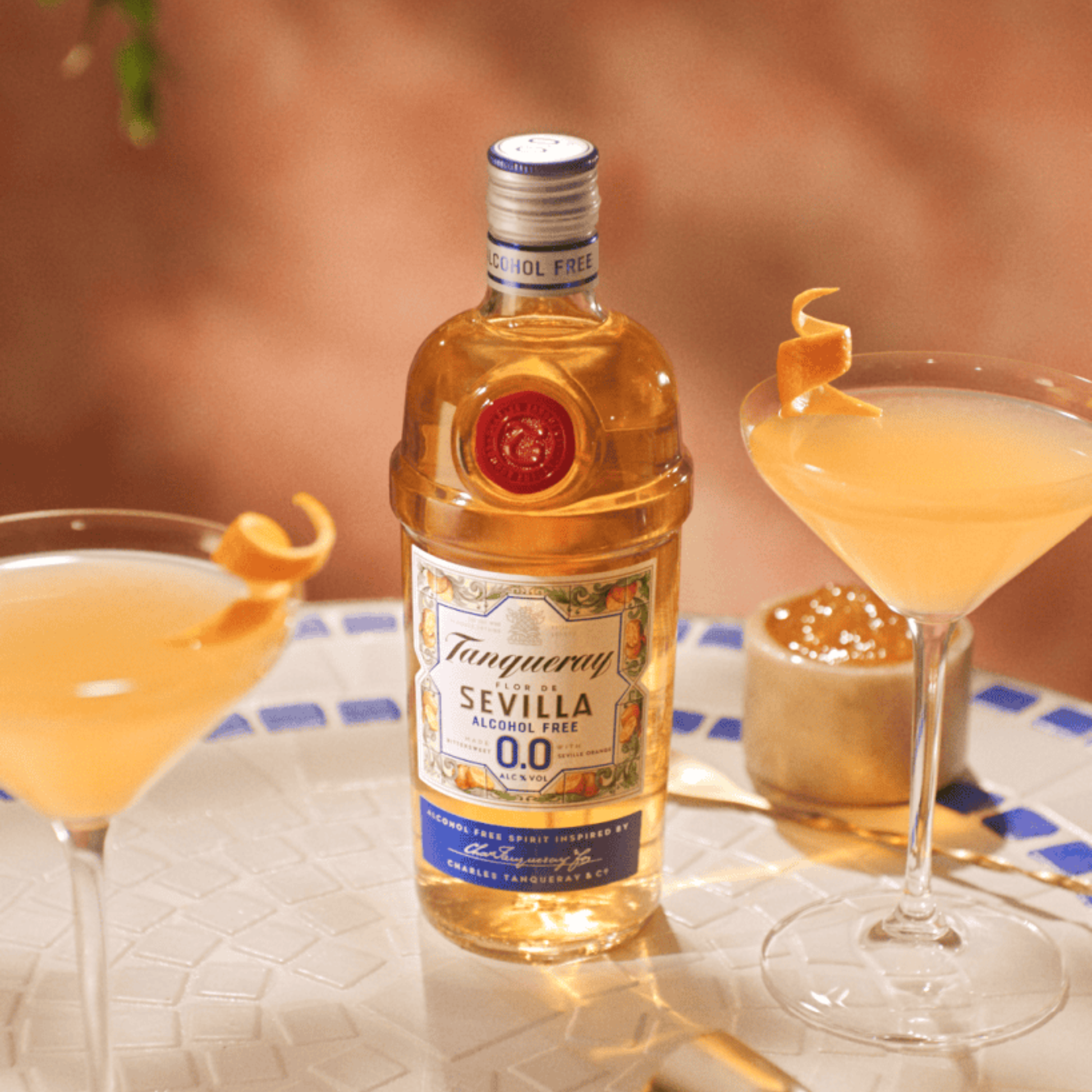 Bottle of Tanqueray Sevilla Alcohol Free gin with cocktails on a table