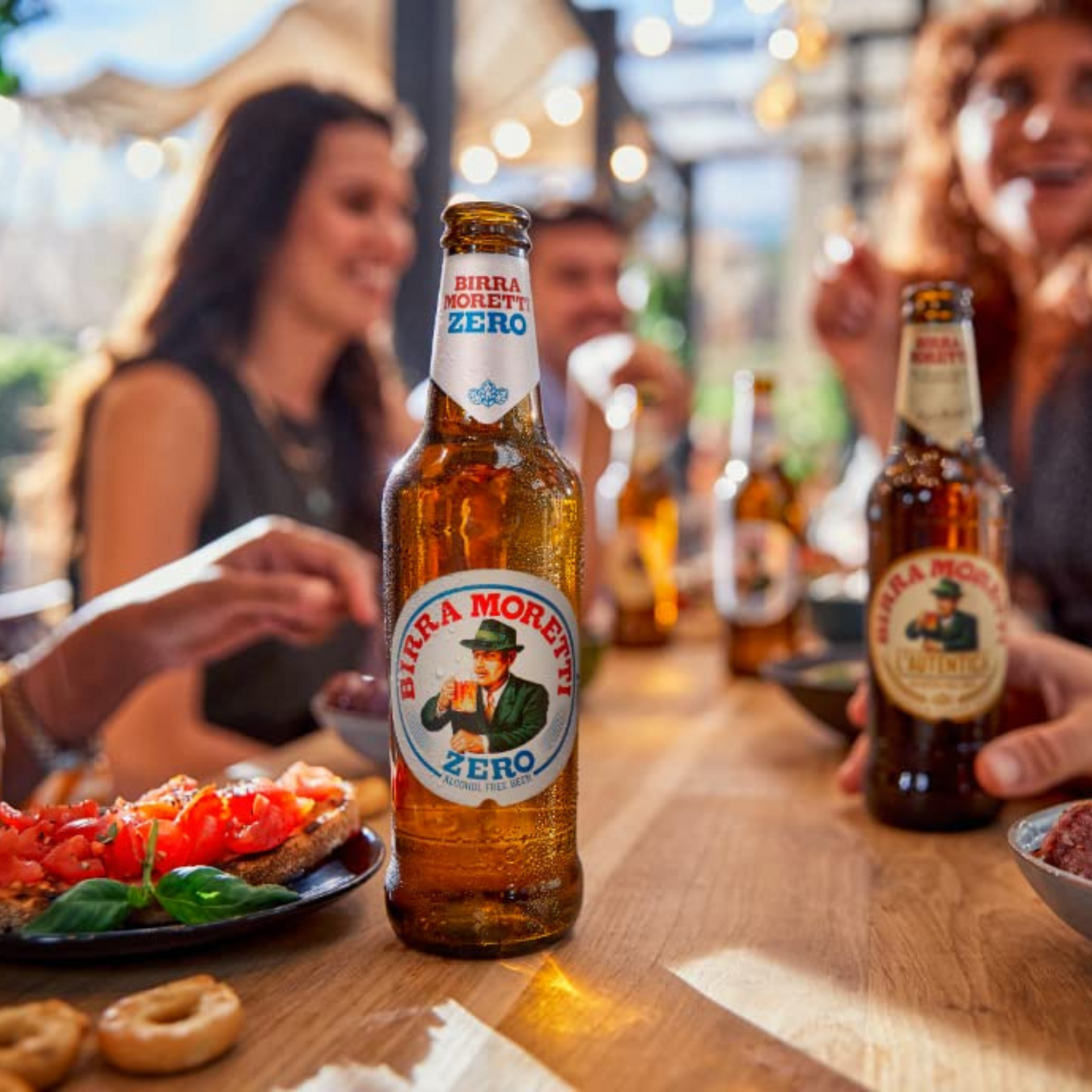 Birra Moretti Zero beer bottle on a table with people in the background